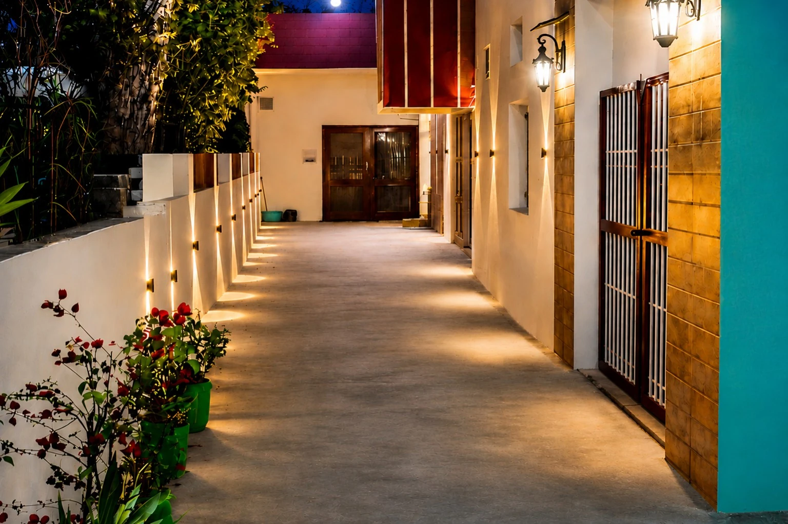 Basant Niwas pathway with warm lantern sconces and garden planters at night